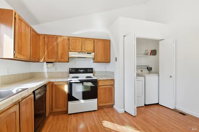 a kitchen with stainless steel appliances granite countertop a stove a sink and a refrigerator with wooden floors