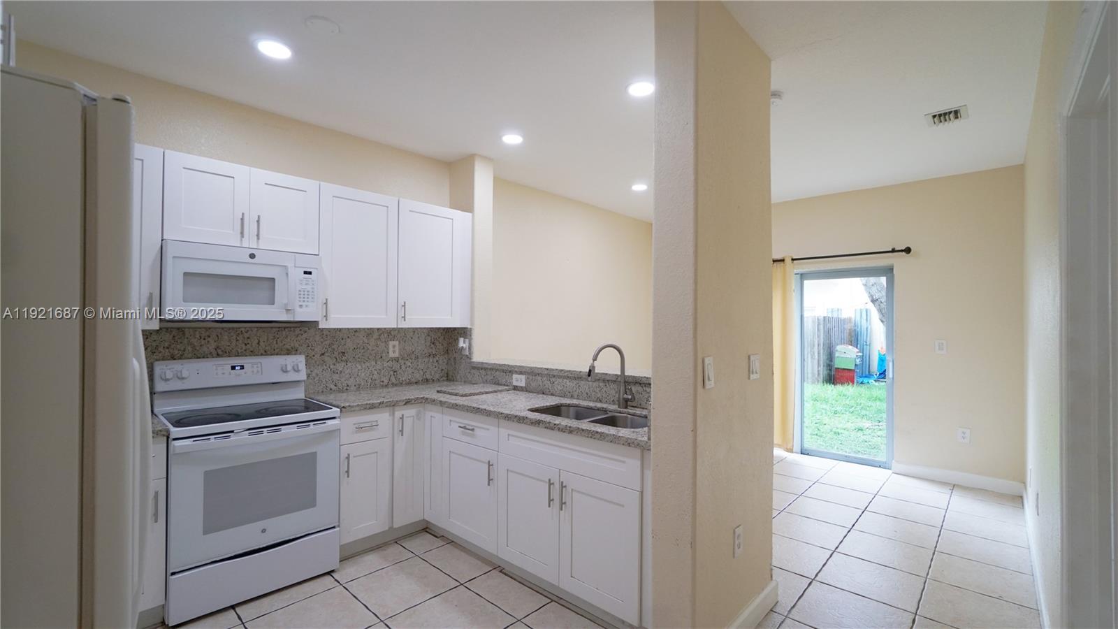 1535 Southeast 26th Street, Unit 103 Homestead, FL 33035 - Photo 14 of 26 a kitchen with white cabinets and white appliances