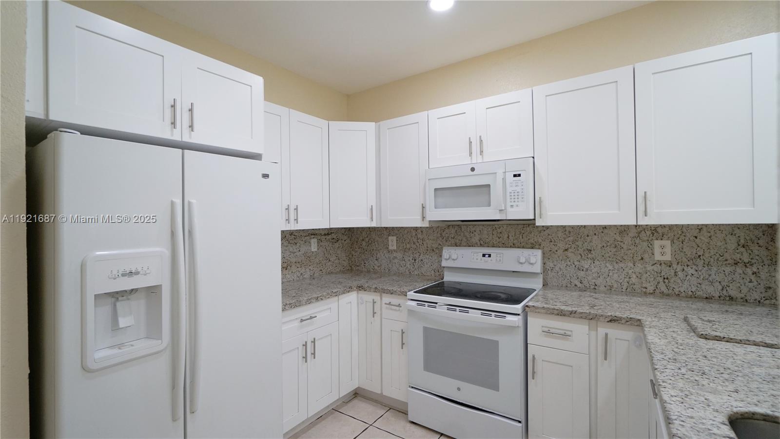 1535 Southeast 26th Street, Unit 103 Homestead, FL 33035 - Photo 17 of 26 a kitchen with white cabinets and white appliances