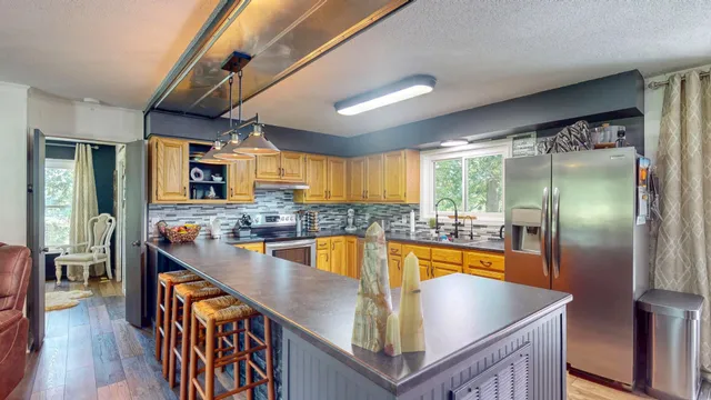 a kitchen with stainless steel appliances granite countertop a sink a stove and a refrigerator