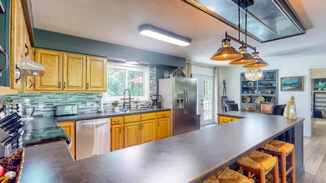 a kitchen with stainless steel appliances granite countertop a sink a stove and refrigerator