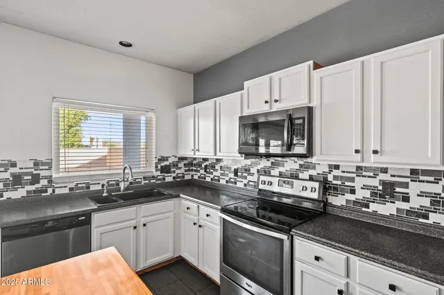 a kitchen with stainless steel appliances a sink dishwasher stove and white cabinets