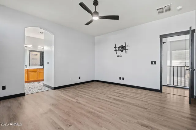 a view of an empty room with window and wooden floor