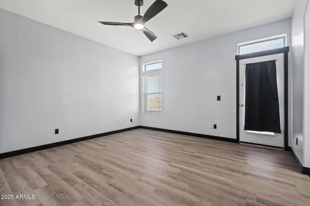 a view of an empty room with wooden floor and closet