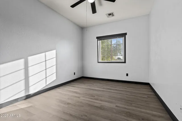 a view of an empty room with a window and wooden floor