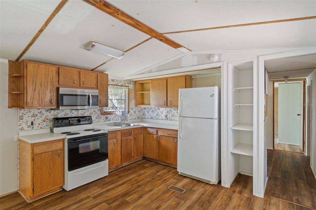 1805 North Paul Drive Inverness, FL 34453 - Photo 5 of 26 a kitchen with stainless steel appliances granite countertop a refrigerator a stove top oven a sink and dishwasher with wooden floor