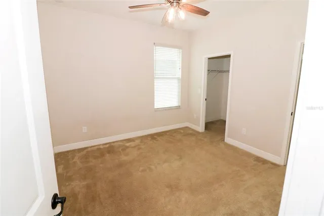 an empty room with windows and chandelier fan
