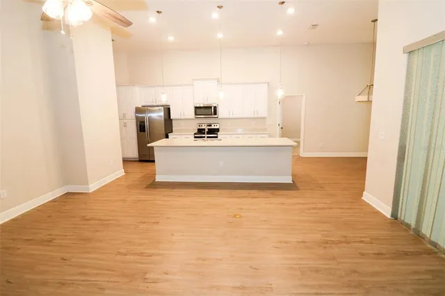 a view of a kitchen with kitchen island a sink wooden floor and a large window