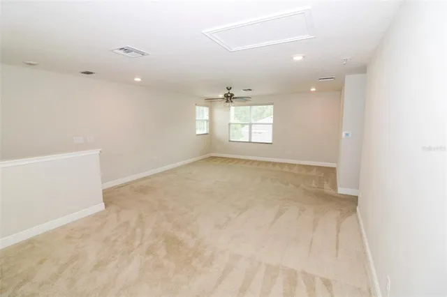 an empty room with windows and chandelier fan