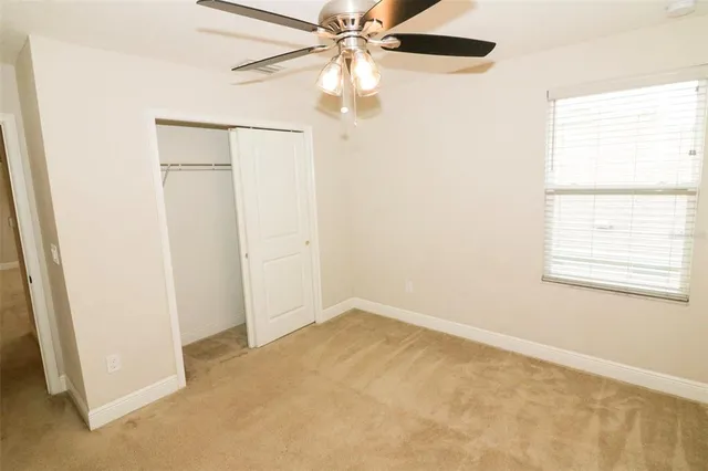 an empty room with a window and a fan