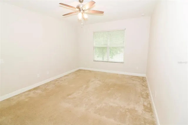 an empty room with a window and a fan