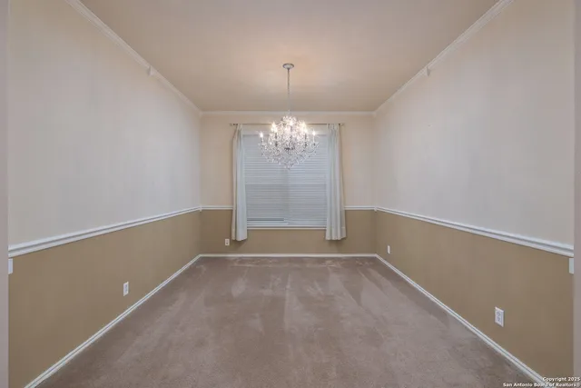 a view of an empty room with window and chandelier fan