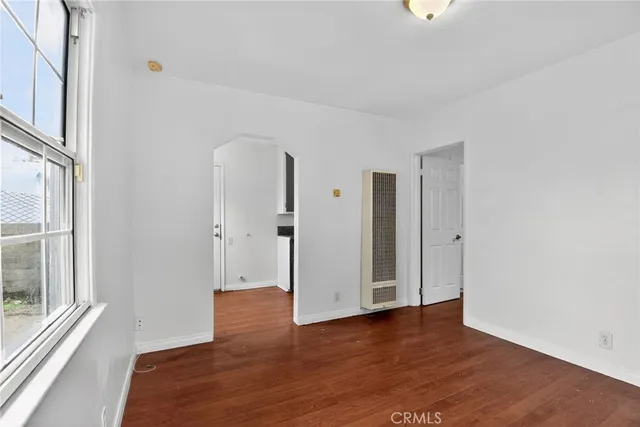 a view of an empty room with wooden floor and windows