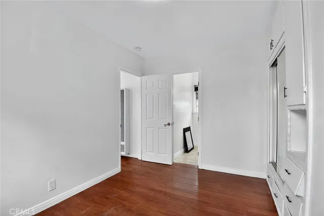 a view of an empty room with wooden floor and window