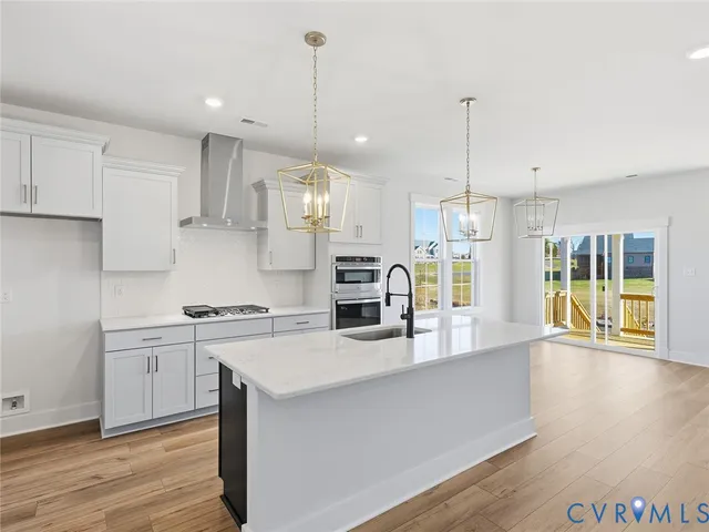 a kitchen with stainless steel appliances granite countertop a sink a stove and a wooden floors