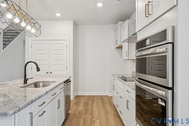 a kitchen with stainless steel appliances granite countertop a sink and dishwasher a stove top oven with wooden floor