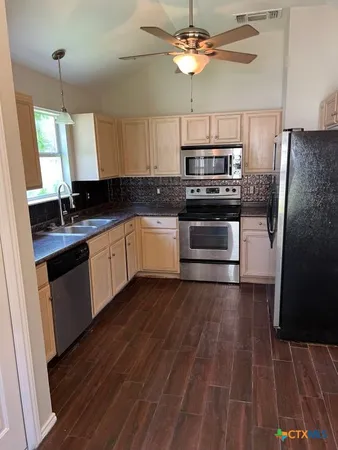 a kitchen with stainless steel appliances a stove a sink and white cabinets