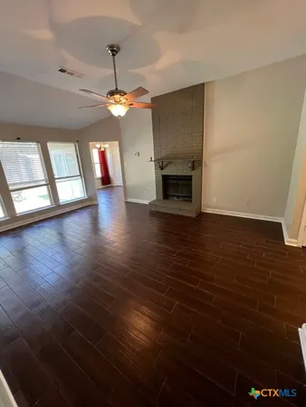 a view of an empty room with wooden floor fireplace and a window