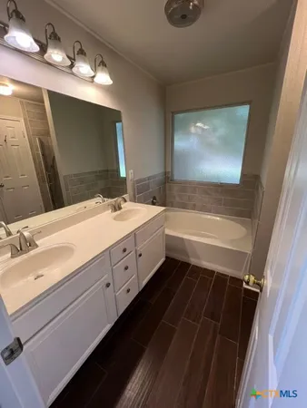 a bathroom with a double vanity sink a mirror and a bathtub