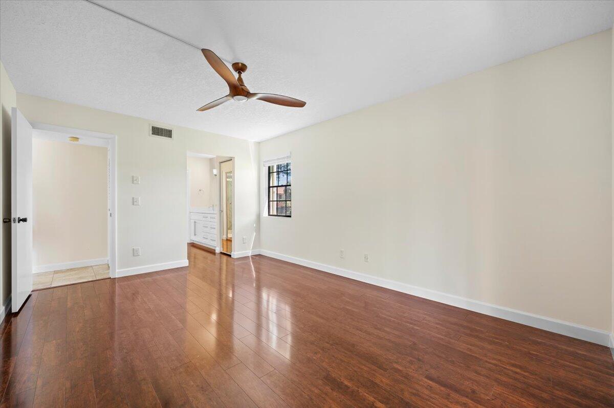 101 Pinecrest Circle, Unit A Jupiter, FL 33458 - Photo 12 of 25 a view of an empty room with wooden floor and a ceiling fan