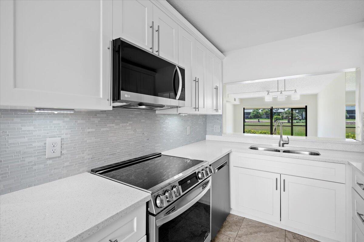 101 Pinecrest Circle, Unit A Jupiter, FL 33458 - Photo 4 of 25 a kitchen with stainless steel appliances a stove microwave and sink
