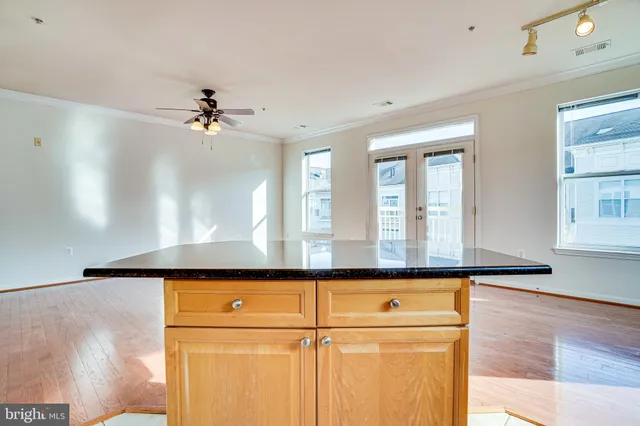 a kitchen with stainless steel appliances a stove top oven a sink a refrigerator white cabinets and wooden floor