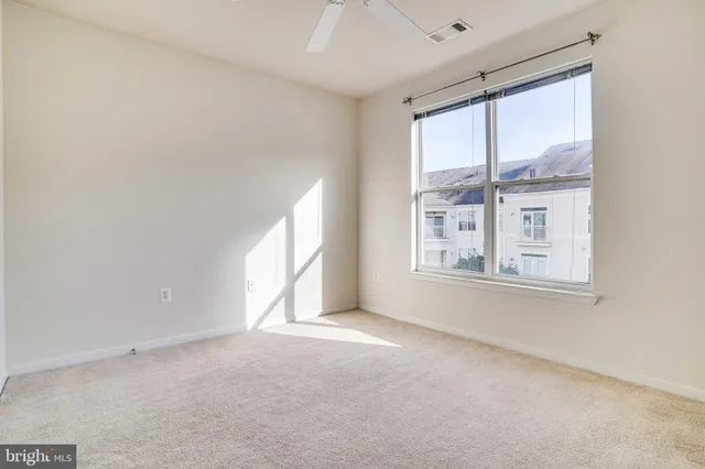 an empty room with a ceiling fan and carpet