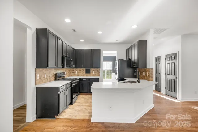 a view of a kitchen with kitchen island a sink wooden floor and a refrigerator