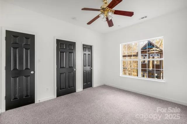 an empty room with windows and fan