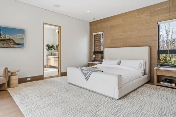 a white bed sitting in a bedroom next to a window with potted plants