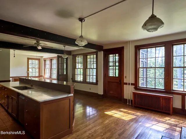 a view of an empty room with wooden floor and windows