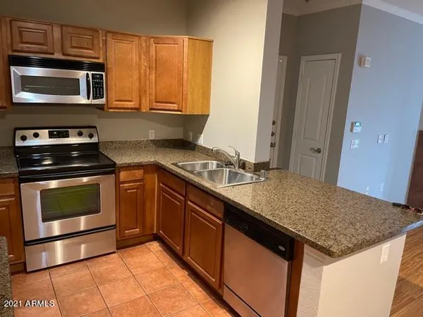 a kitchen with stainless steel appliances granite countertop a refrigerator a stove and a sink with wooden floor