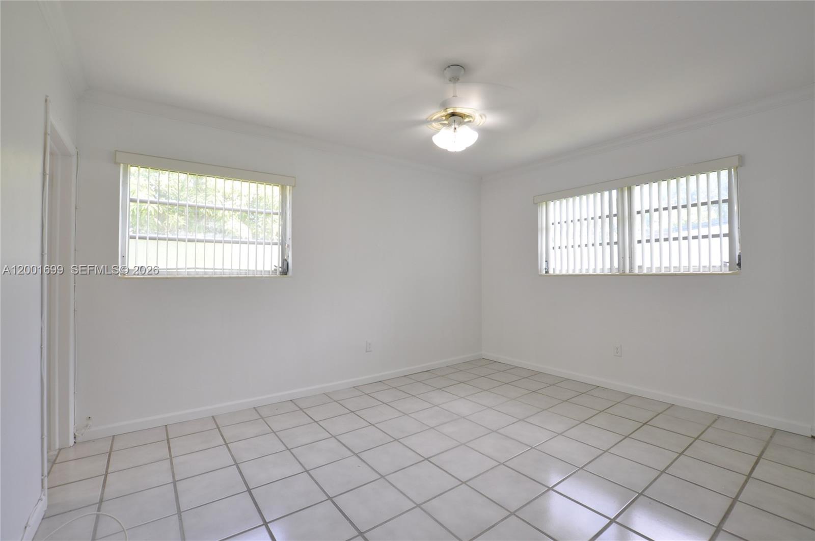 11111 Southwest 78th Court Pinecrest, FL 33156 - Photo 14 of 19 an empty room with windows and chandelier fan
