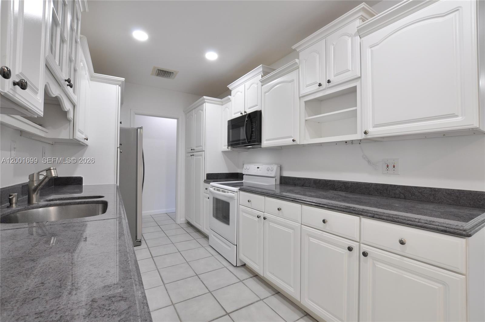 11111 Southwest 78th Court Pinecrest, FL 33156 - Photo 10 of 19 a kitchen with granite countertop a sink a stove and refrigerator