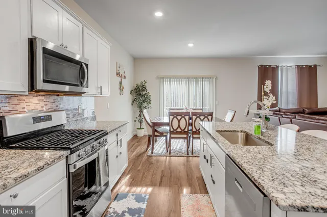 a kitchen with stainless steel appliances granite countertop a stove a sink and a microwave