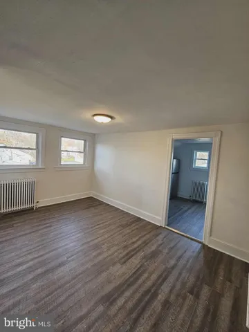 a view of an empty room with wooden floor and window