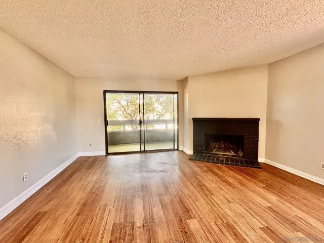 an empty room with wooden floor fireplace and windows