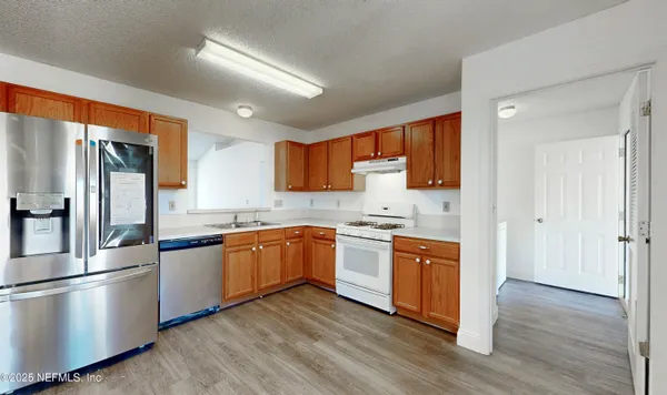 a kitchen with stainless steel appliances granite countertop a refrigerator a stove top oven a sink and dishwasher with wooden floor