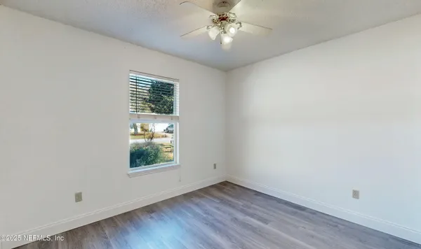 an empty room with wooden floor chandelier fan and windows