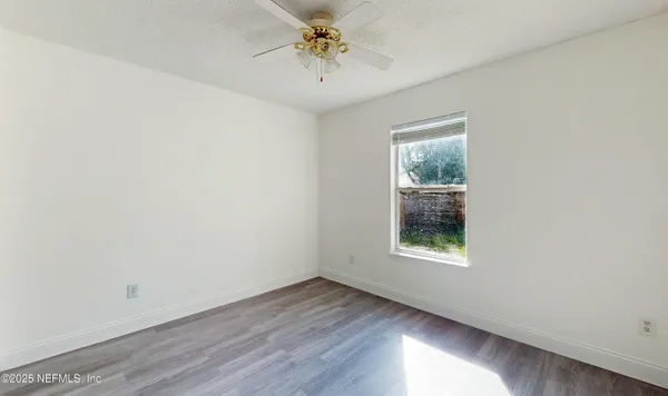 an empty room with windows and chandelier fan