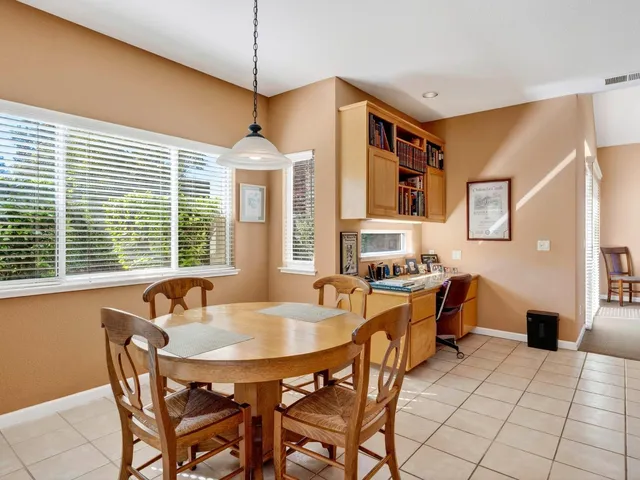 a kitchen with stainless steel appliances granite countertop a stove top oven a sink a dining table and chairs