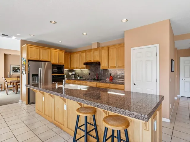 a kitchen with granite countertop a table chairs microwave and cabinets