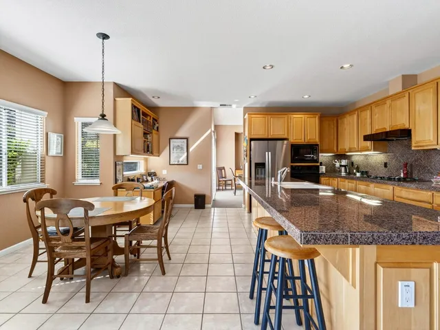 a large kitchen with stainless steel appliances granite countertop a stove top oven a sink and dishwasher