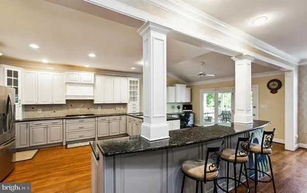 a kitchen with granite countertop a stove a sink a dining table and chairs