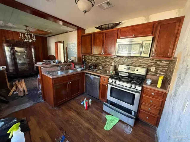 a kitchen with stainless steel appliances a stove a sink dishwasher and cabinets with wooden floor