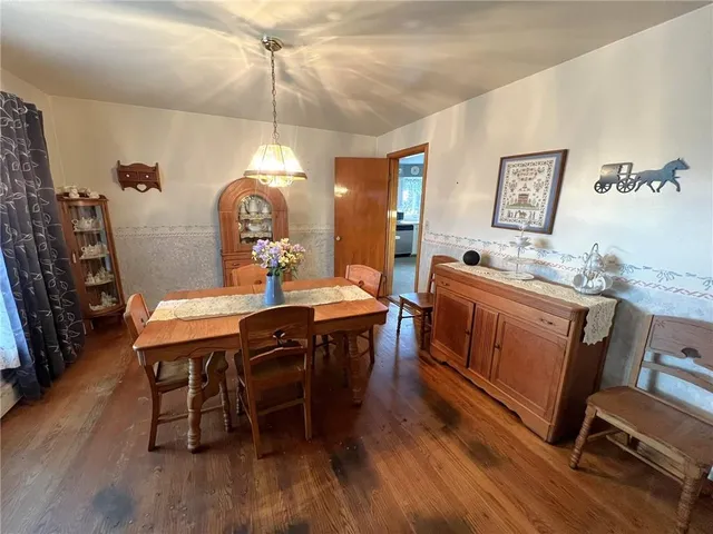 a dining room with wooden floor a chandelier a wooden table and chairs