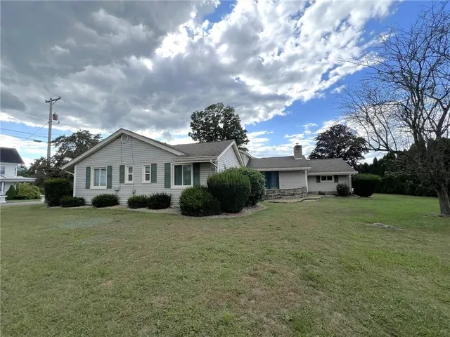 a view of a house with a big yard and a large tree