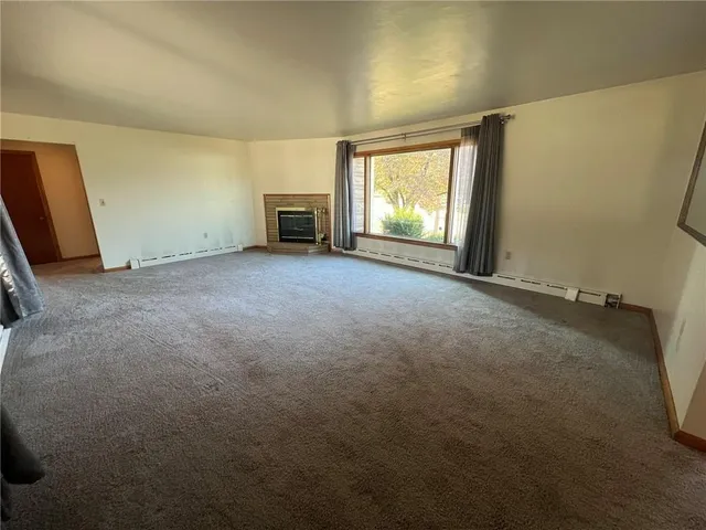 an empty room with windows and fireplace