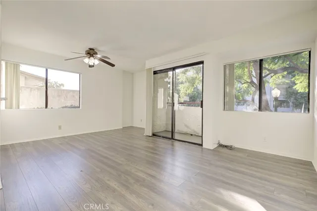 a view of an empty room with a window and wooden floor