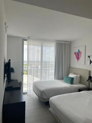 a bedroom with two beds and a large window